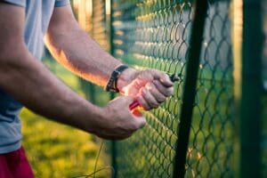 Worker performing a fence repair on a chainlink fence